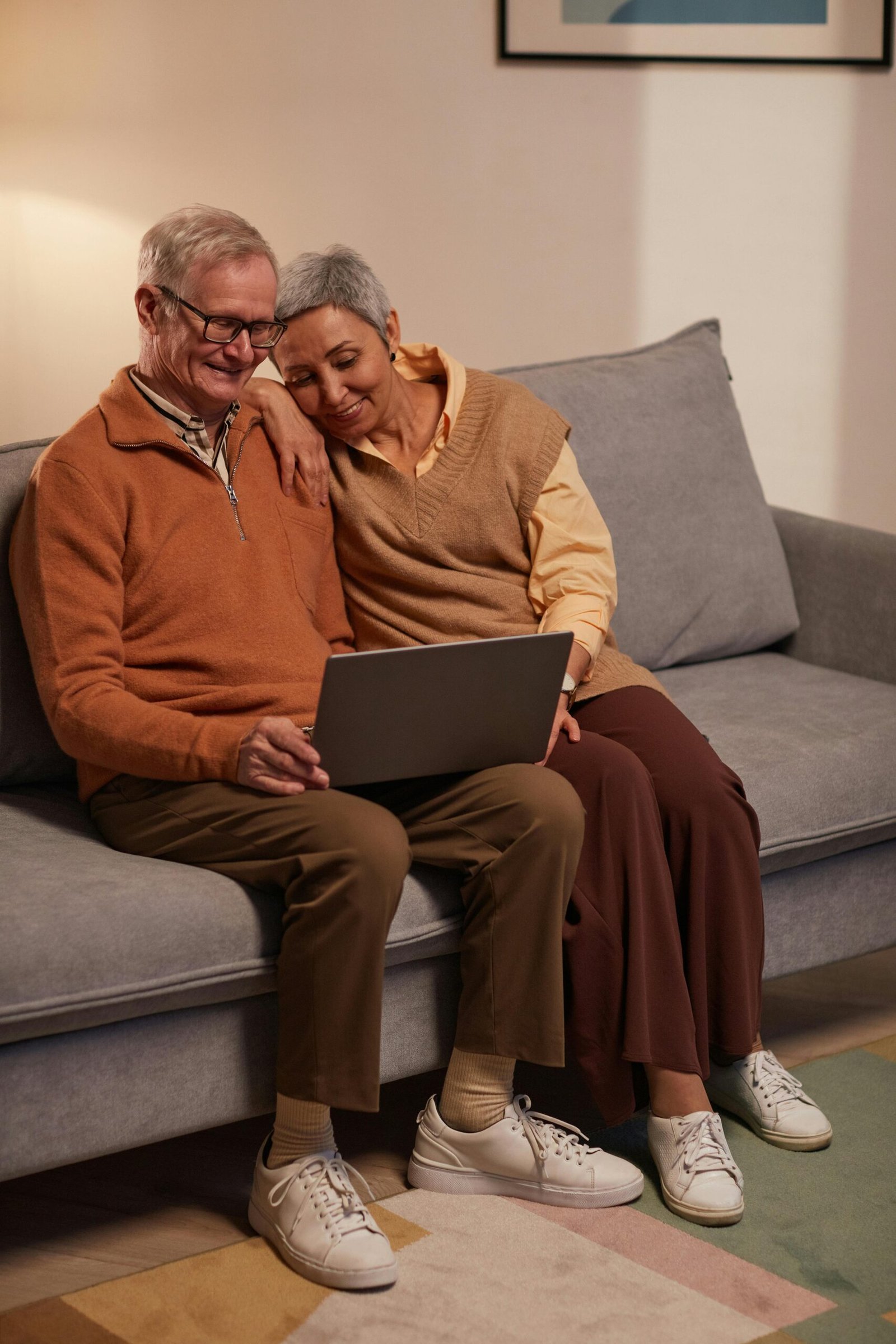 Senior couple enjoying time together on the couch with a laptop, indoors.