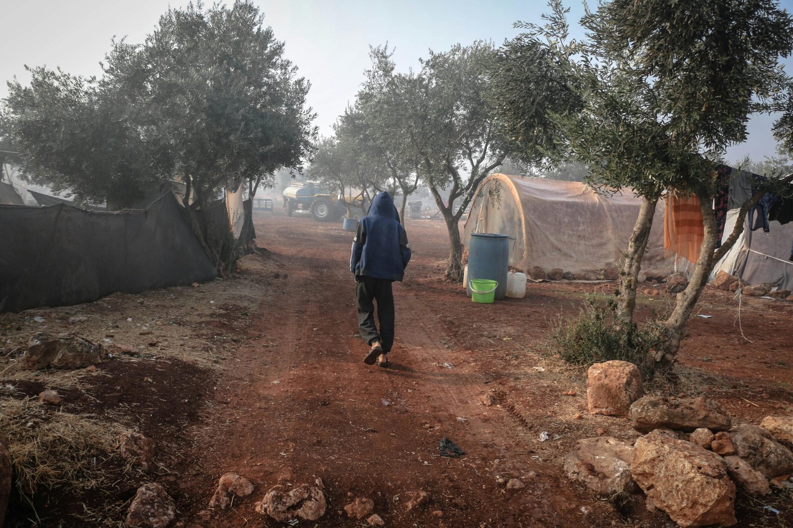 A person walks through a refugee camp, showcasing daily life.