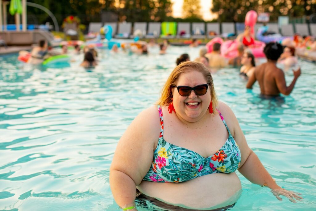 woman wearing blue and red floral bikini top on pool, obesité, surpoids, plaisir, soourires